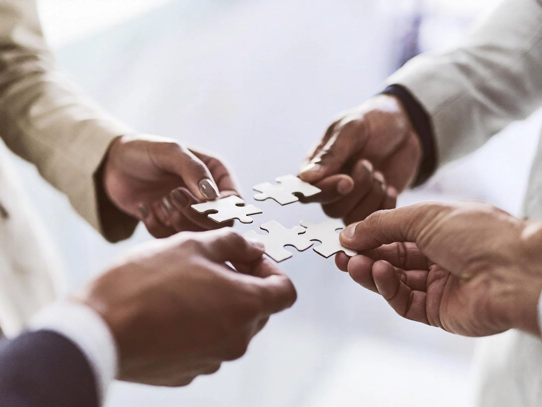 Quattro mani uniscono i pezzi di un puzzle