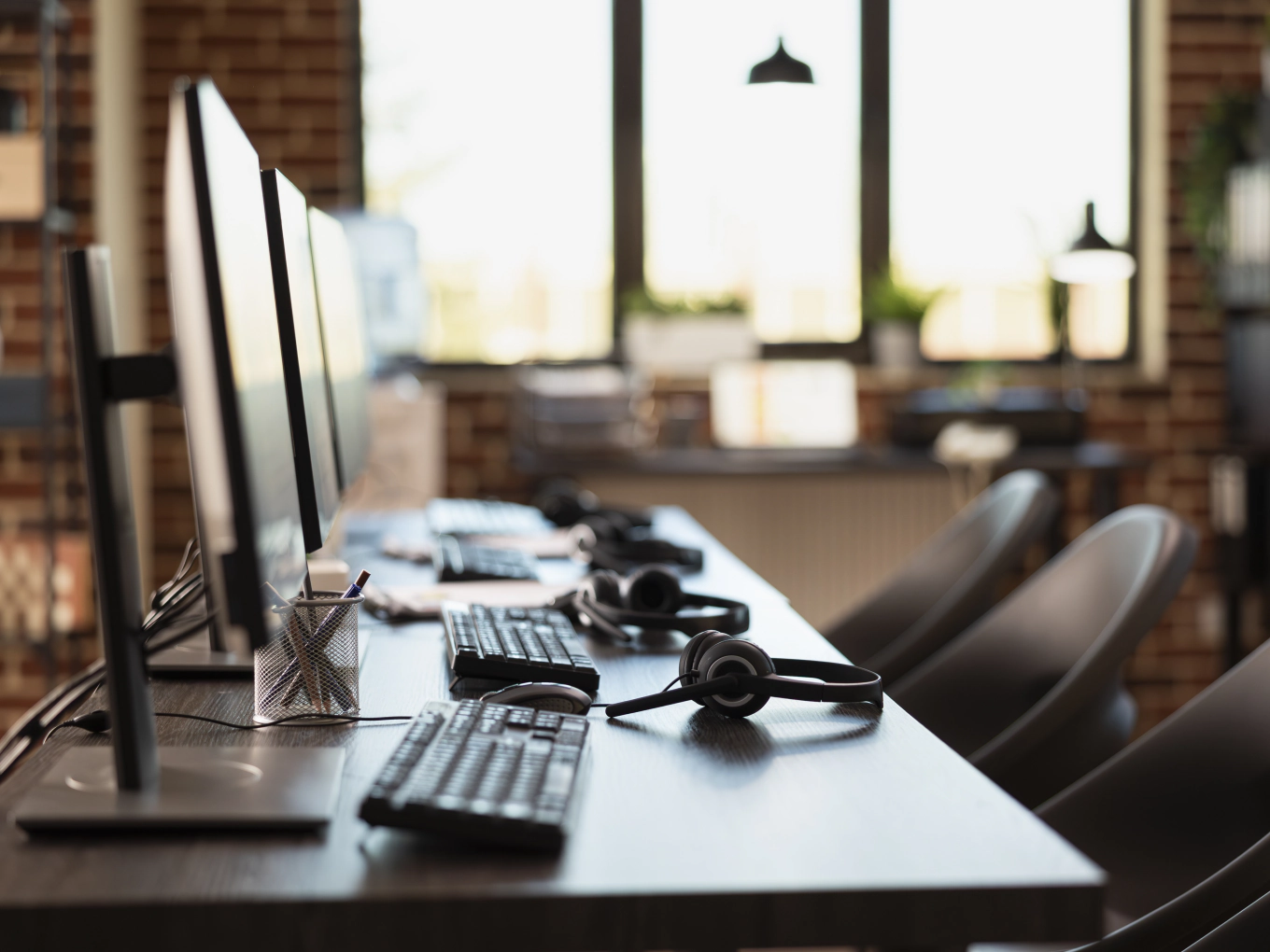 Postazioni di lavoro con monitor, tastiere e cuffie allineate in un ufficio operativo